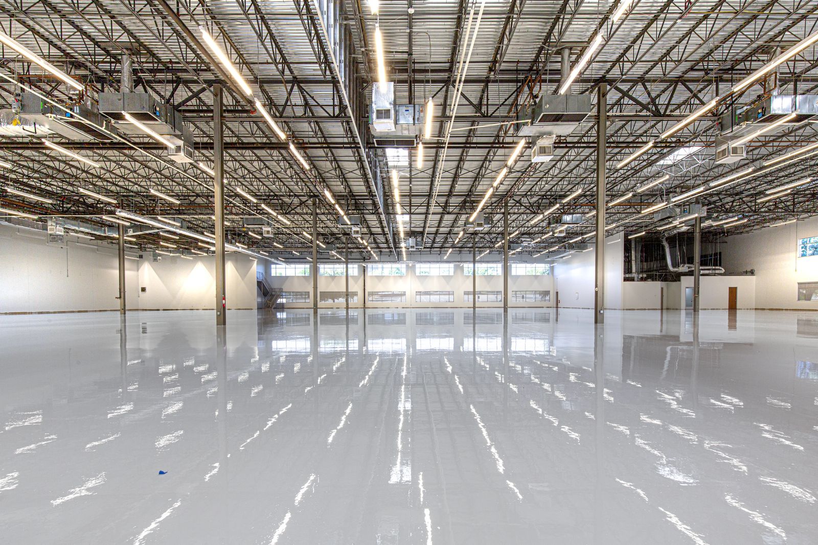Large commercial facility with a freshly coated high-gloss gray epoxy floor reflecting overhead lights