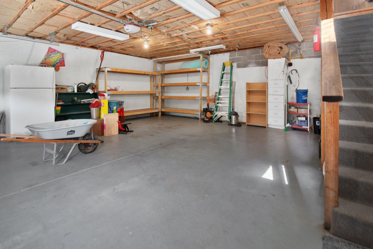 Residential garage with bare concrete floor and storage shelving, before any epoxy coating